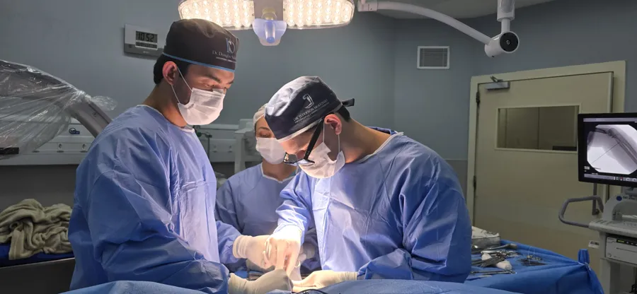 Dr. Jeferson Moitinho operando com a equipe, com o monitor de imagem ao fundo